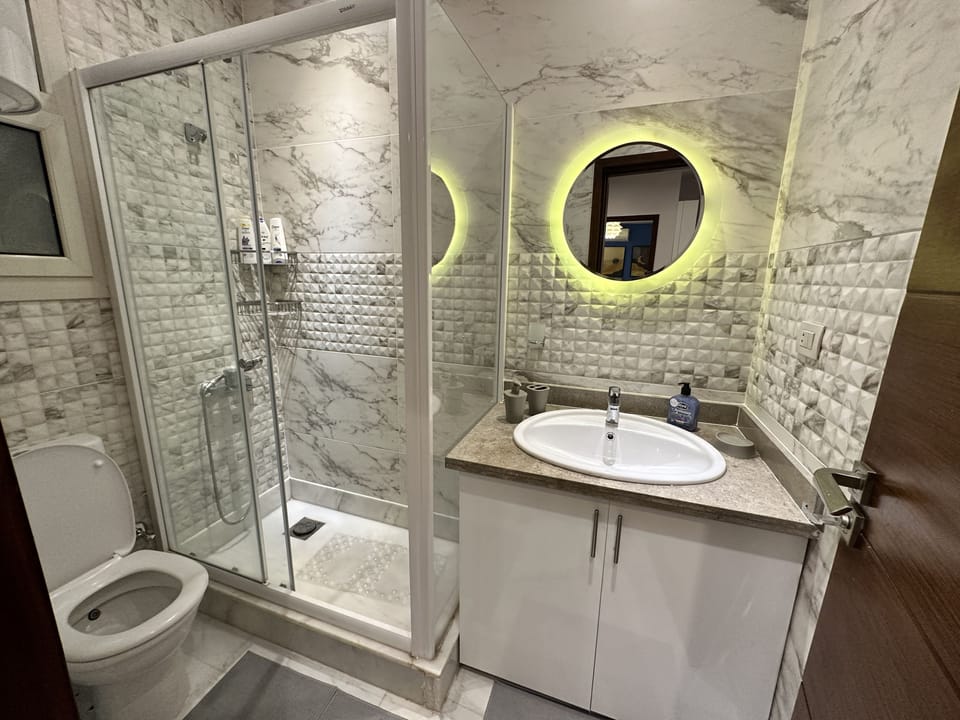 Bathroom with an enclosed shower, sink and toilet.