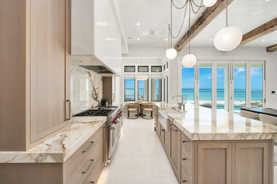 Your dream kitchen awaits with marble countertops and ocean views through floor-to-ceiling windows, perfect for morning coffee.