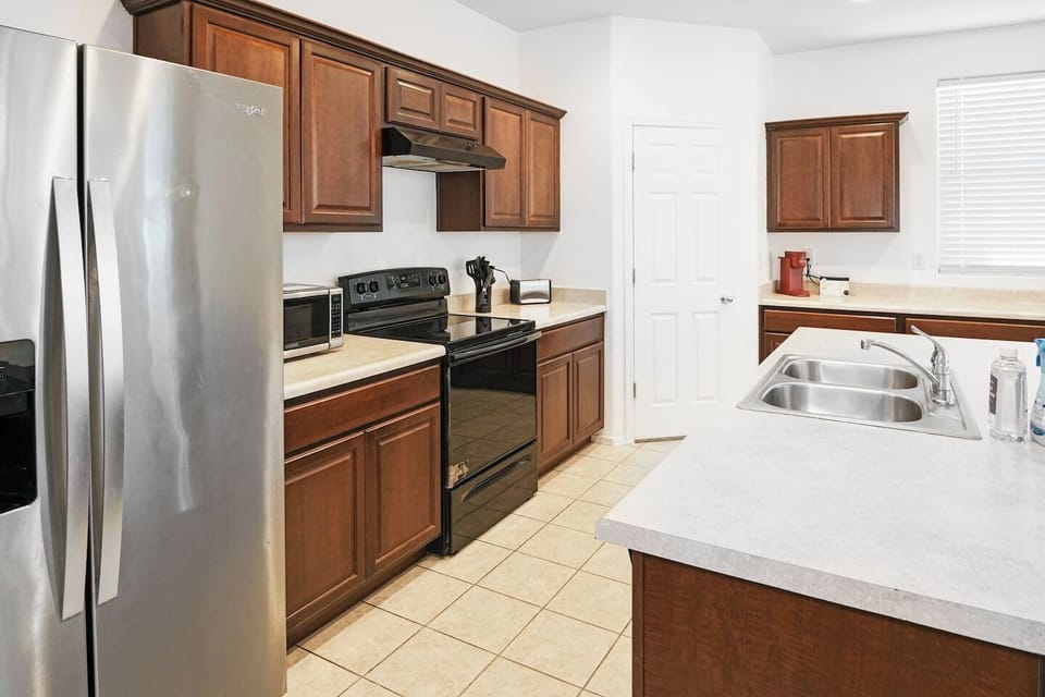 Kitchen with fridge, stove, microwave, cabinets, and island sink