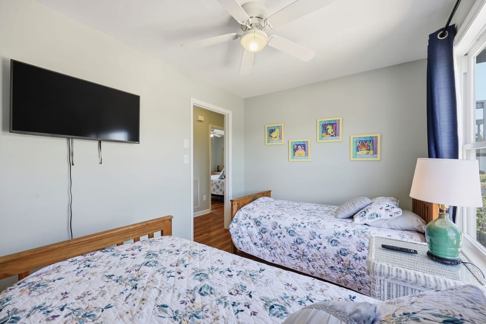 Relax in your cozy bedroom with comfortable beds, cheerful artwork, and modern conveniences like a flat-screen TV and ceiling fan to keep you comfortable during your stay.