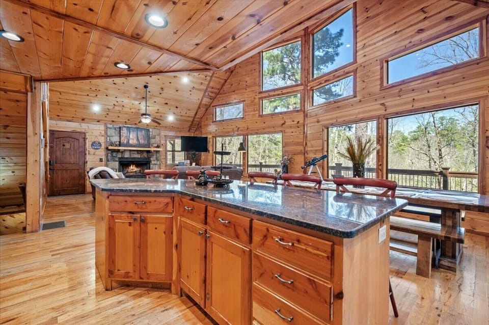Open-concept wood interior with telescope, stone fireplace, and forest-facing