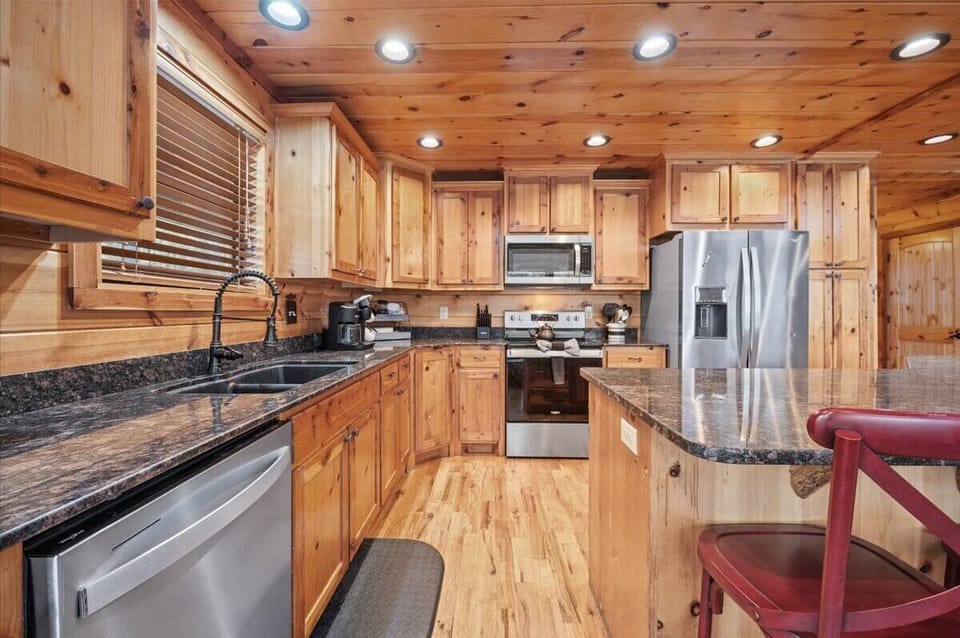 Wood-paneled kitchen with granite counters, stainless appliances, red accents