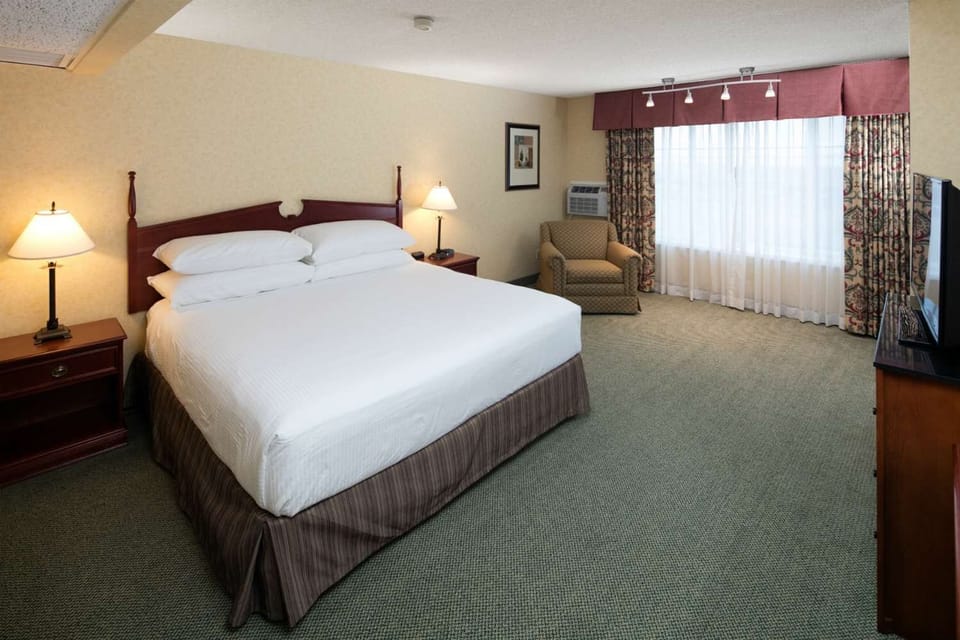 Unwind in a spacious room with crisp linens and lounge chair.