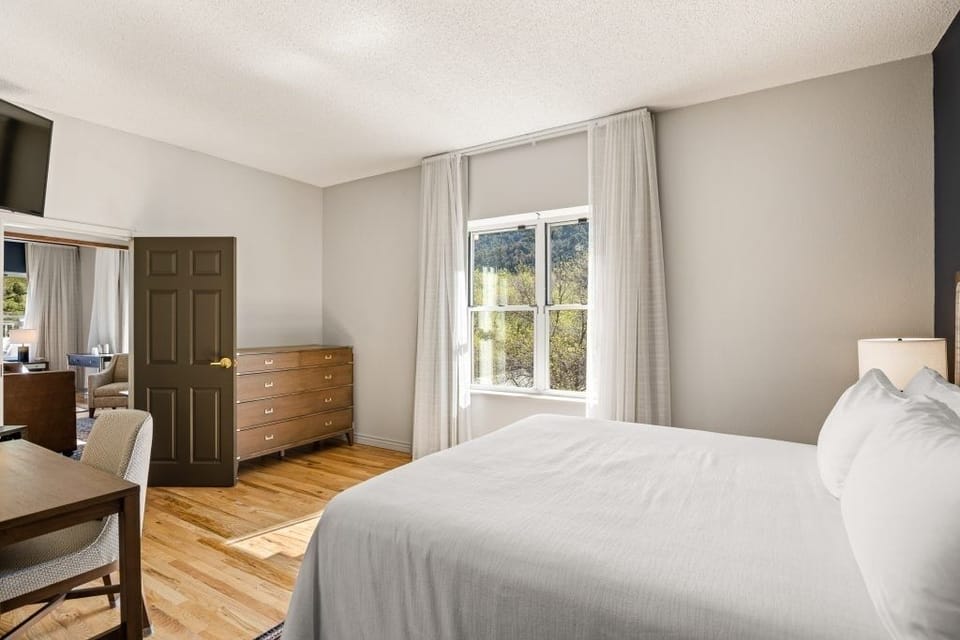 Unwind in crisp linens with sunlight on hardwood floors.