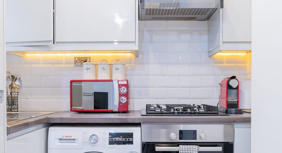 Modern fully equipped kitchen featuring an oven, hob, microwave, coffee machine and washing machine for added convenience during your stay.