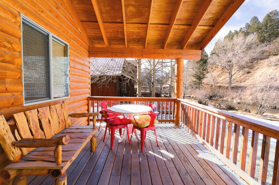 Step onto your private covered deck with hillside vistas—rustic log bench and cheerful red dining set await your morning coffee or sunset gathering in the crisp mountain air.