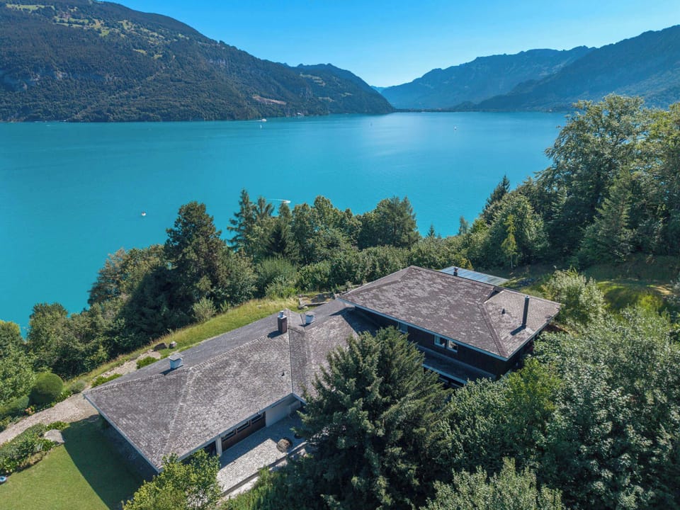 Aerial view of the villa surrounded by Lake Thun, forests, and the beautiful Bernese Alps.
