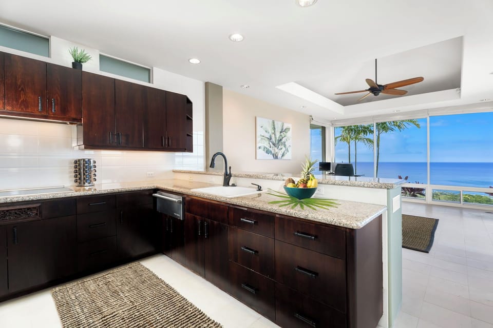 Cook with endless ocean views through floor-to-ceiling windows in your sleek modern kitchen with granite counters and premium appliances.