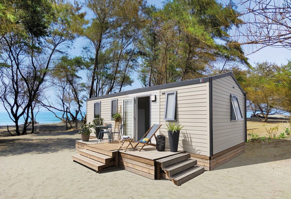 Surrounded by trees, the stylish mobile home features a spacious outdoor deck, perfect for enjoying the coastal breeze.