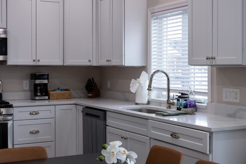The bright and airy kitchen, with its sleek white cabinetry and modern appliances, invites families to gather and create cozy meals together.