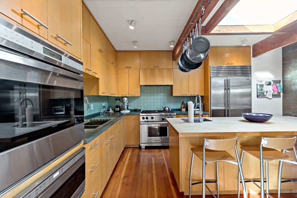 Full kitchen view with island seating and ample storage, a practical hub for your Cape Cod vacation rental stay.