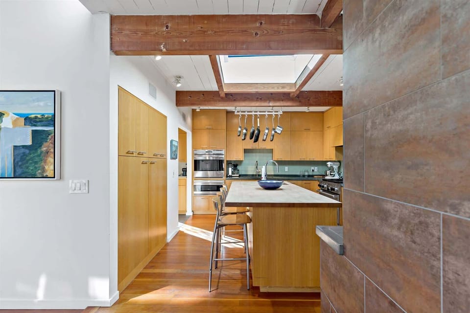 Bright kitchen with a skylight, hanging pot rack, and an oversized island, made for Cape Cod vacation cooking.