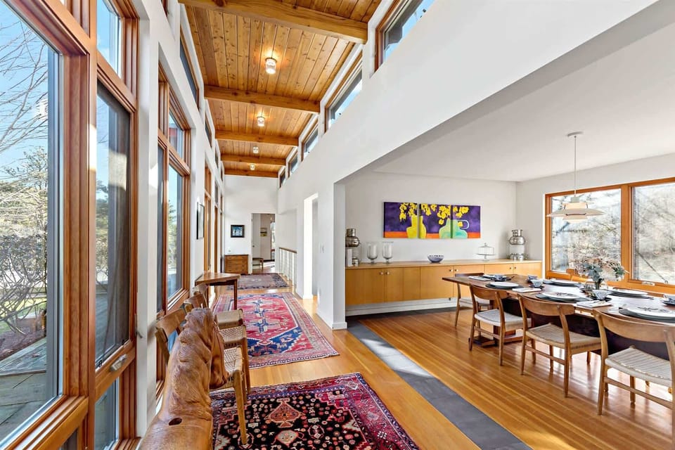 Sunlit hallway with tall windows and warm wood ceiling details, showcasing classic mid-century modern Cape Cod style.
