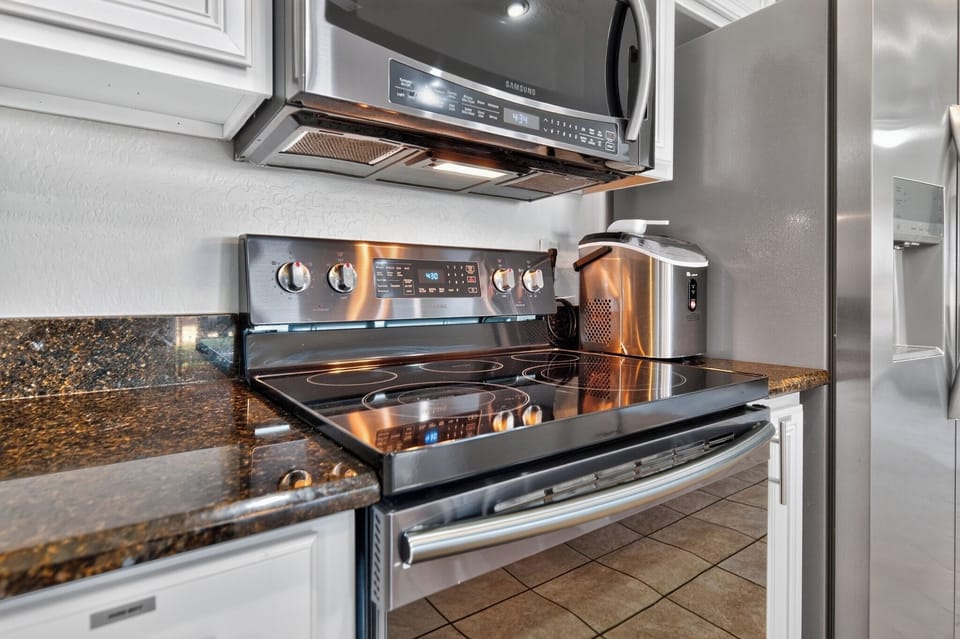 Microwave, electric stove, oven, freezer, and refrigerator for easy meal prep.