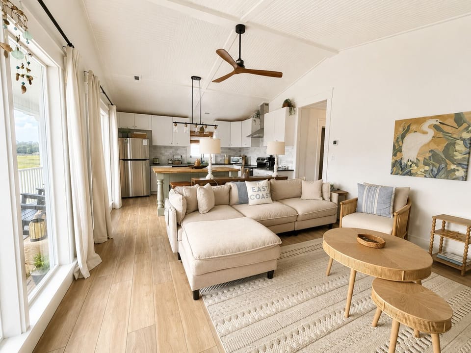 Bright, open living area with plush seating, vaulted ceiling, and kitchen access