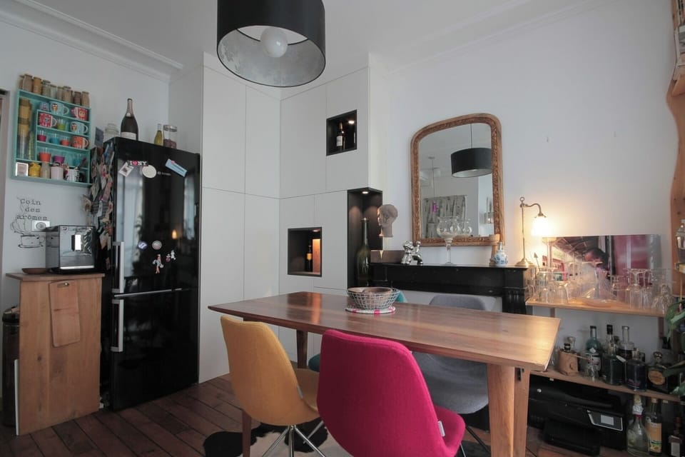 Espace repas & bureau – Salle à manger conviviale avec table en bois et chaises colorées, et coin bureau parfait pour télétravailler en plein cœur de Pigalle.