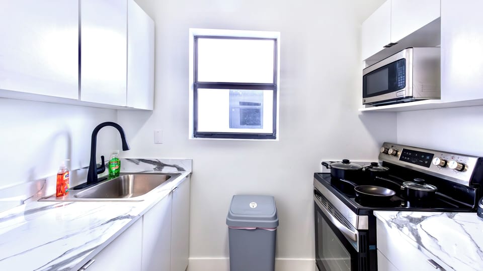 Fully equipped modern kitchen featuring a stove with cookware, microwave. #vibes