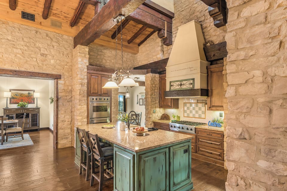 A chef-inspired kitchen blends stone walls, exposed beams, and a statement island—perfect for slow mornings and wine-country feasts.