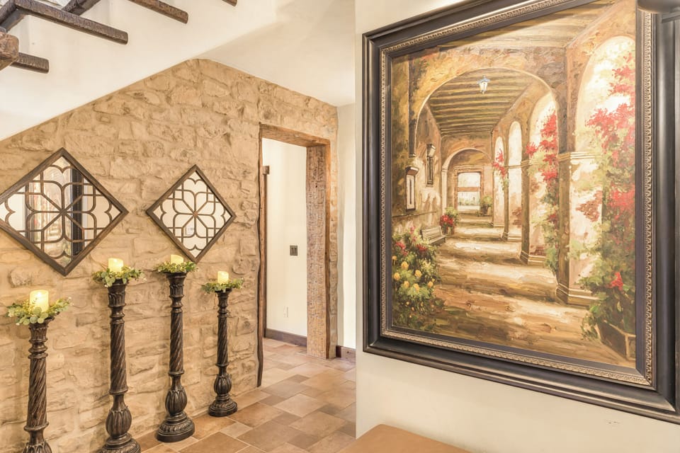 A sunlit gallery hallway with arched windows and exposed beams.