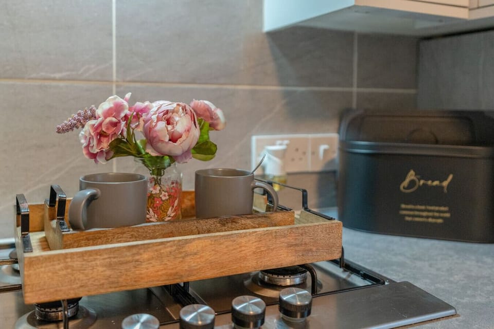 Make tea or coffee with mugs and a tray set out on the kitchen hob