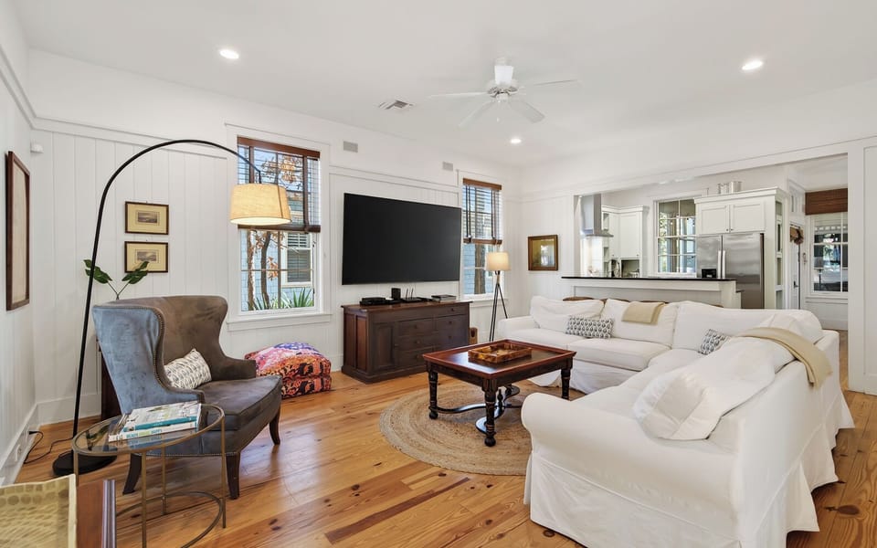 Sink into the plush white sectional sofa and unwind in this light-filled living space with gleaming hardwood floors and thoughtful touches.