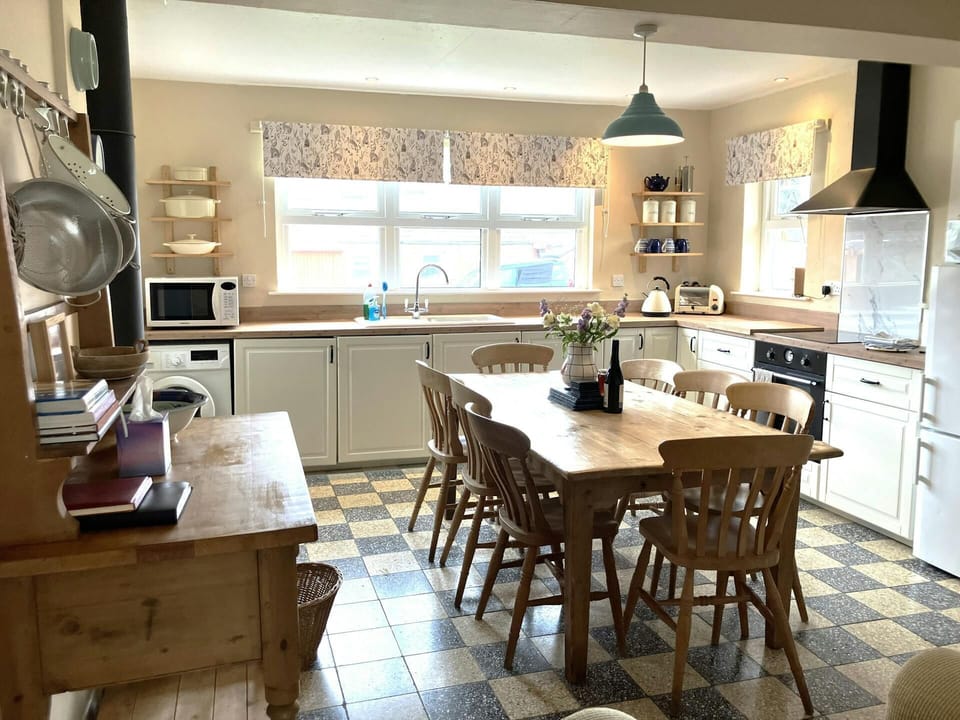 Fitted kitchen/dining area: wooden dining table with eight chairs, stove and extractor hood, microwave, fridge/freezer, washing machine, kettle and toaster