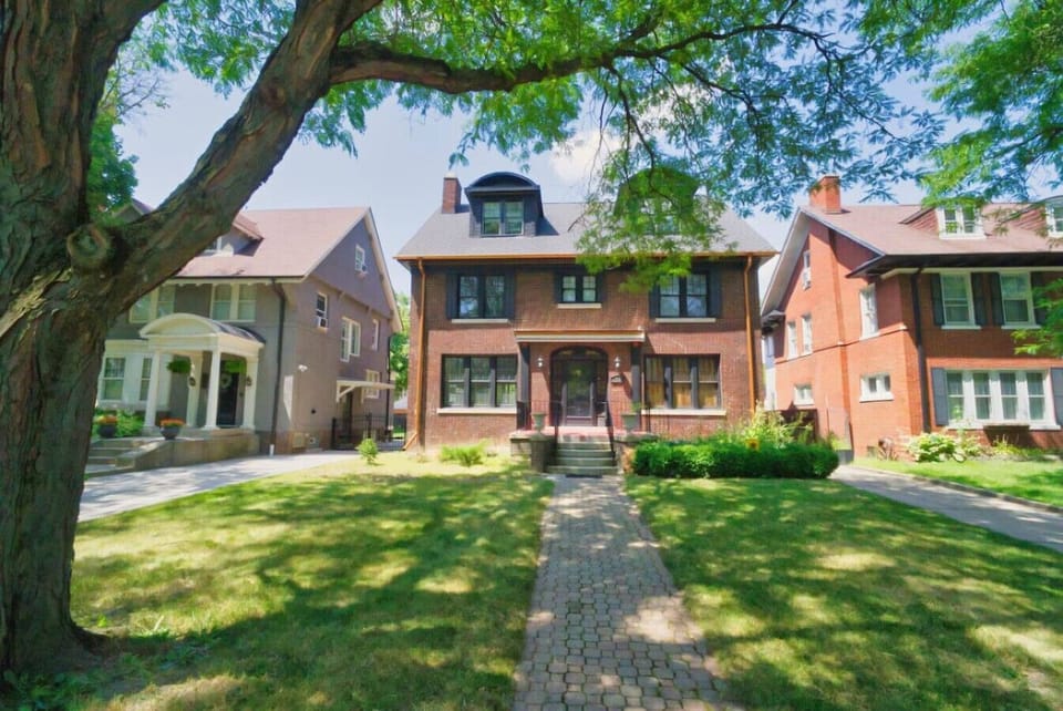 A stately historic home with three levels, framed by leafy surroundings and old-world character.