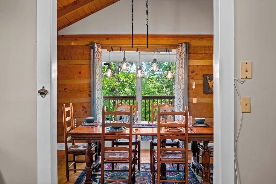 Tucked beneath a glowing chandelier, this window-framed dining space brings the outdoors in. Enjoy your meals with a side of forest views and plenty of cabin charm.