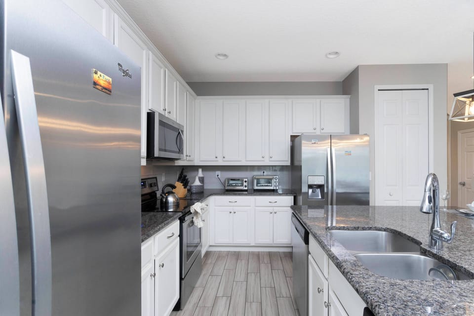Experience a beautifully designed kitchen featuring stainless steel appliances, elegant white cabinetry, and stunning granite countertops.