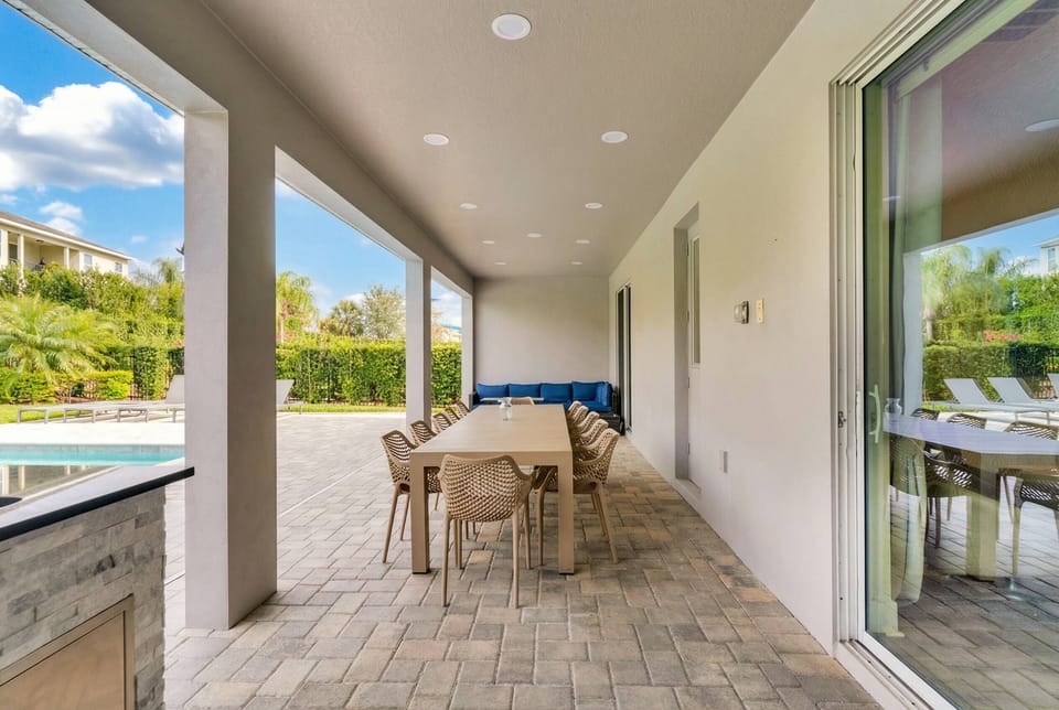 Enjoy a covered patio with outdoor dining, cozy lounge seating, pool views, and direct access to the backyard, creating a comfortable space for meals and relaxing in the Florida sun.