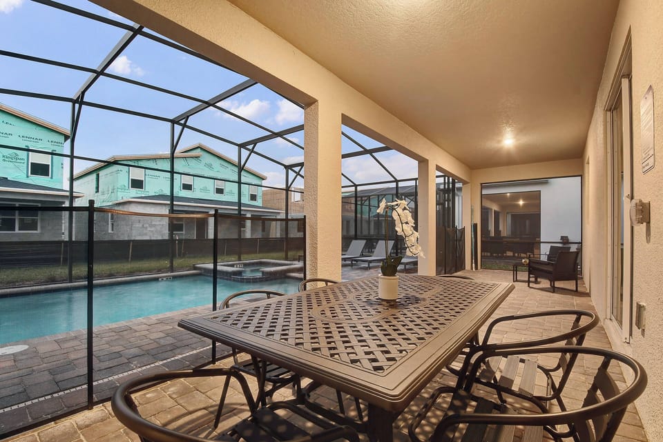 Enjoy our spacious screened patio with a stylish metal dining table and comfy chairs, ideal for al fresco meals. Take in the serene pool view and relax under soft evening lighting that creates a welcoming atmosphere.