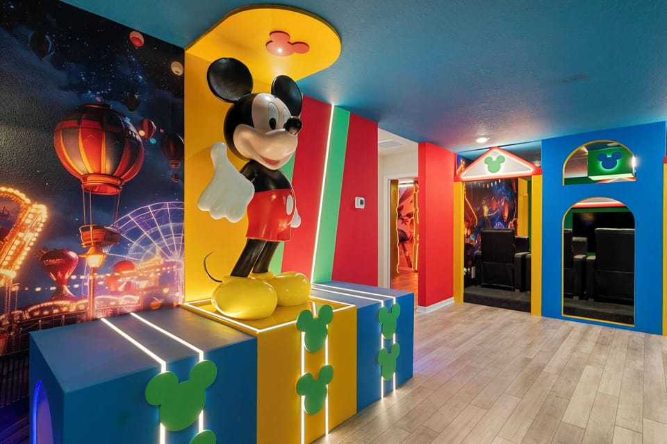 Welcome to a vibrant playroom filled with color, highlighted by a striking Mickey Mouse centerpiece and imaginative wall murals. The bold blue and yellow accents make this space perfect for energetic family fun.