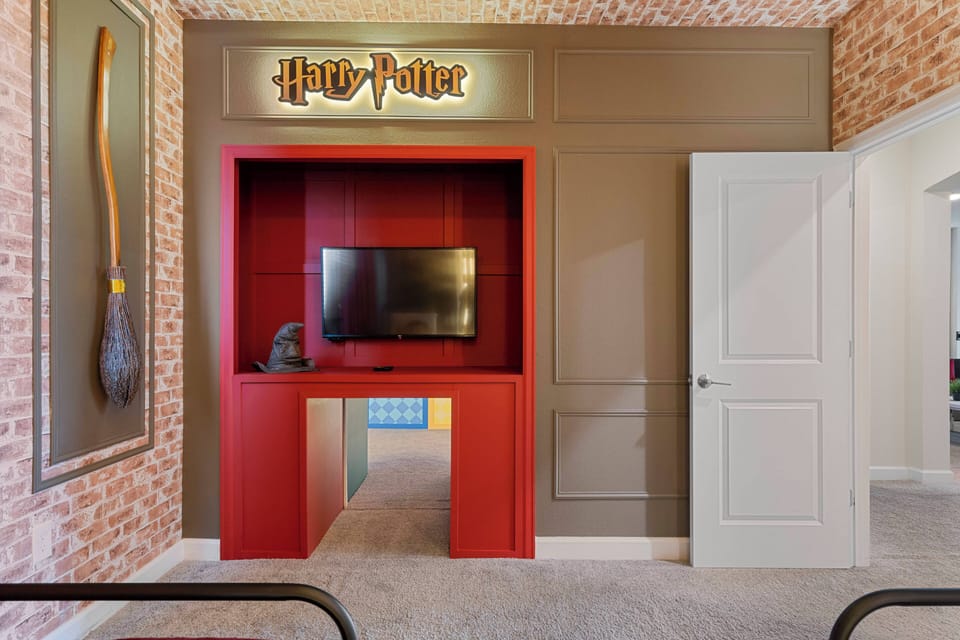 Discover a whimsical space that embraces the magic of the wizarding world, with a vibrant red entertainment console and cozy brick accents, creating a playful atmosphere perfect for fun and imagination for guests of all ages.