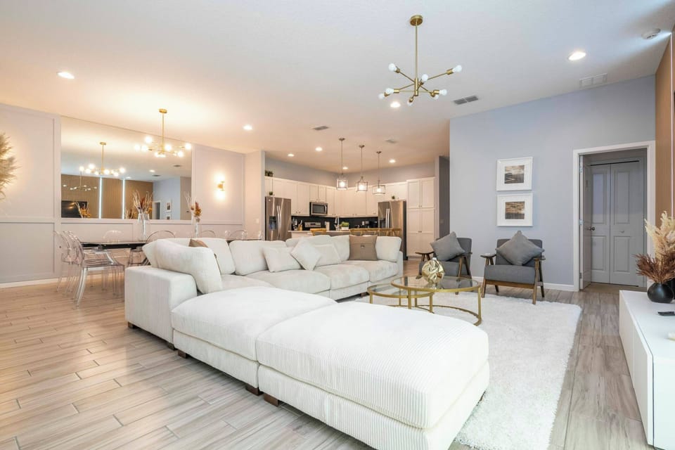 Step into a spacious living area featuring a plush, L-shaped sofa and sleek, modern lighting that sets a welcoming tone. The soft, neutral palette enhances the open layout, while chic accents add a touch of sophistication.