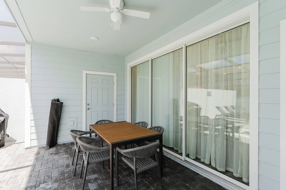 Step outside to a lovely patio with a stylish wooden table for al fresco dining. Enjoy the cool breeze from the ceiling fan while soaking in the natural light pouring through the large glass doors, creating a delightful.