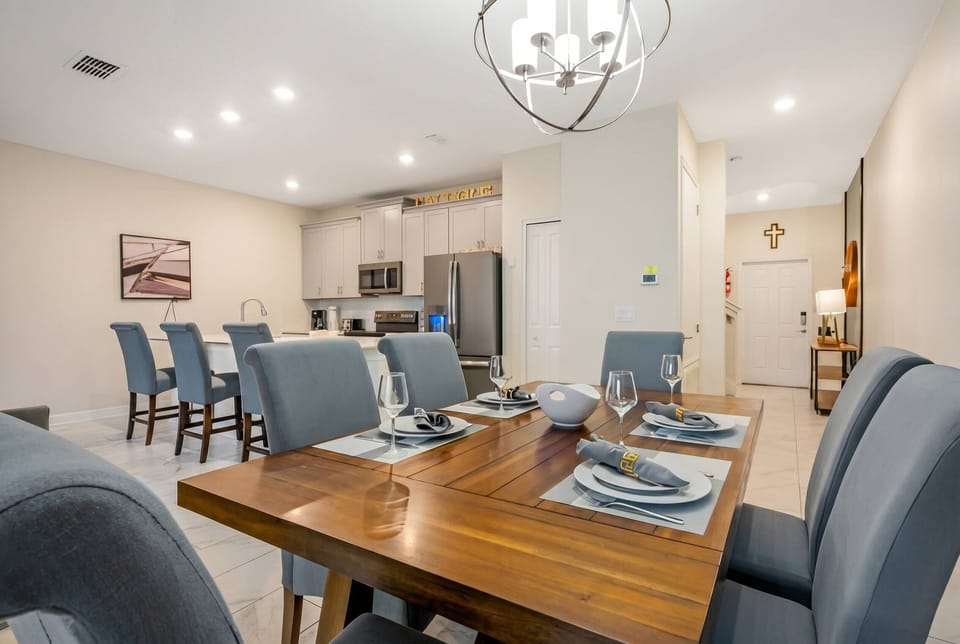 Enjoy a stylish dining area with a rich wooden table and comfortable grey upholstered chairs. The bright, modern kitchen features contemporary appliances and soft lighting, perfect for meals and gatherings.