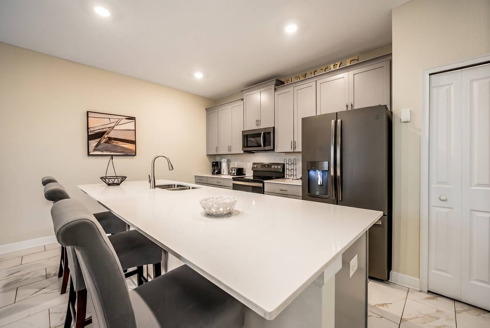 Enjoy our sleek kitchen with a spacious white island perfect for casual dining and stylish gray bar stools. Modern appliances and soft lighting create a bright space ideal for meal prep or savoring your morning coffee.