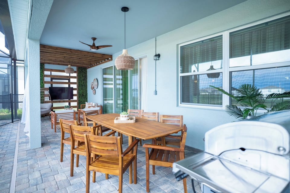 Enjoy al fresco dining under a stylish ceiling fan in this charming outdoor space. A rustic wooden table invites shared meals, while calming green accents and potted plants create a refreshing atmosphere for relaxation.