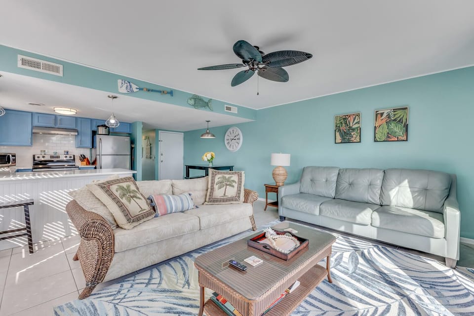 Sink into coastal comfort in your bright living space, where tropical turquoise walls and ocean-inspired decor create the perfect beach retreat atmosphere.