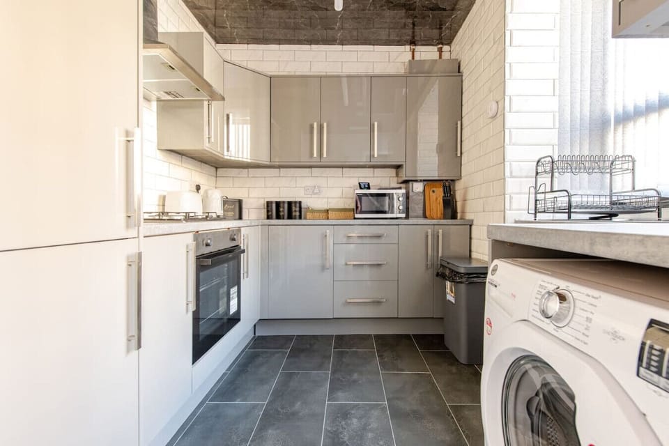 Bright fitted kitchen with oven, worktops, and a washing machine.