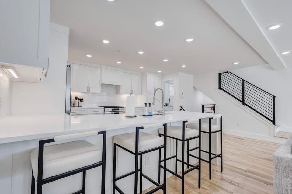 Modern, bright kitchen with a large island, stylish bar stools, and sleek white finishes—perfect for cooking, dining, and gathering.