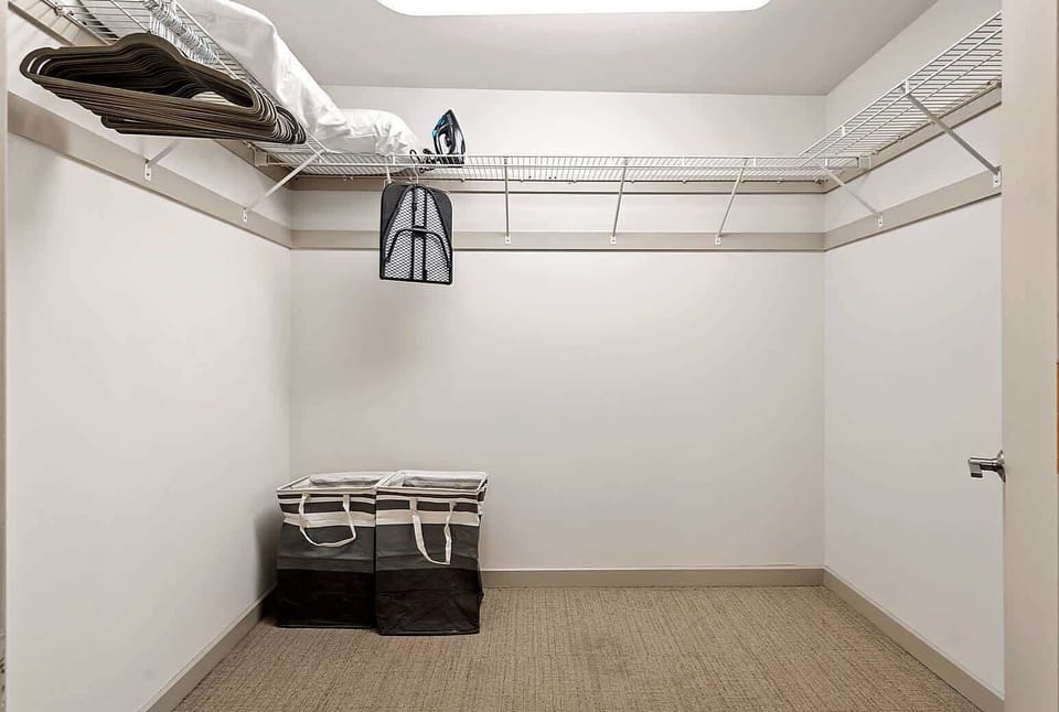 A convenient storage closet located inside the bedroom bathroom, offering ample space for luggage, clothing, and personal items. Includes shelving with extra linens, an iron, and laundry essentials to keep your stay organized and comfortable.