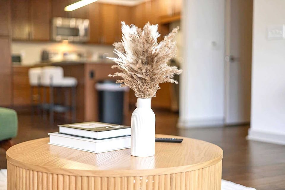 Thoughtfully styled living room detail featuring a modern coffee table with curated decor. Warm wood floors and soft natural light create a welcoming space that feels calm, comfortable, and perfect for relaxing between city adventures.