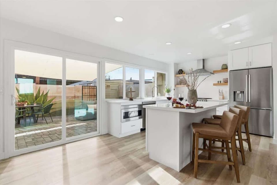 Fully equipped kitchen with stainless steel appliances, bar seating for three, and a coffee bar with a drip coffee maker and a mini fridge.