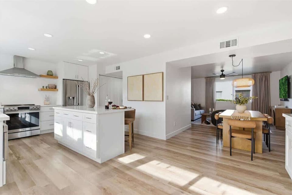 Fully equipped kitchen with stainless steel appliances, bar seating for three, and a coffee bar with a drip coffee maker and a mini fridge.