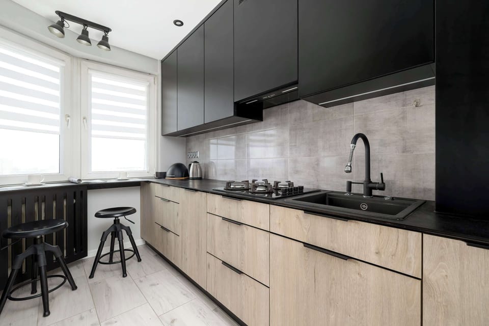 Contemporary kitchen with black and wood cabinetry, bar seating, and clean finishes.