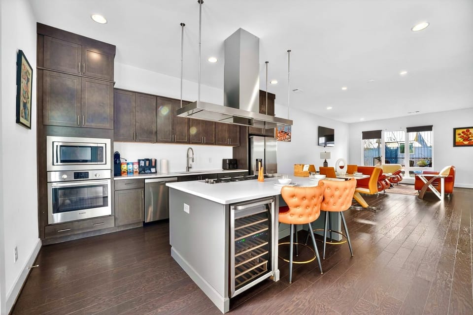 Modern open kitchen with island seating, wine fridge, and bright dining space