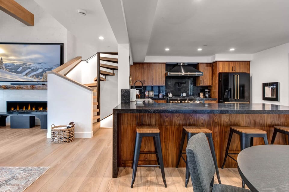 You'll love cooking and gathering in this stunning open kitchen with rich wood cabinetry, sleek black countertops, and bar seating.