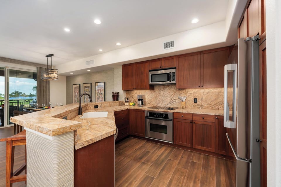 Your gourmet kitchen awaits with granite counters, premium appliances, and tropical views - perfect for morning coffee or evening meals.
