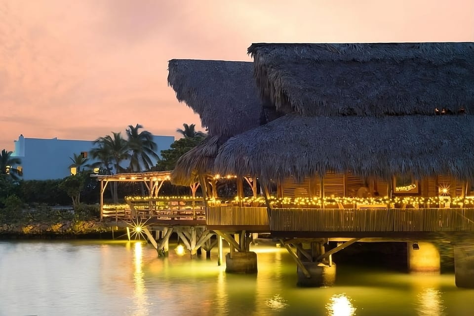 Dine over the water as lights sparkle on calm waves.